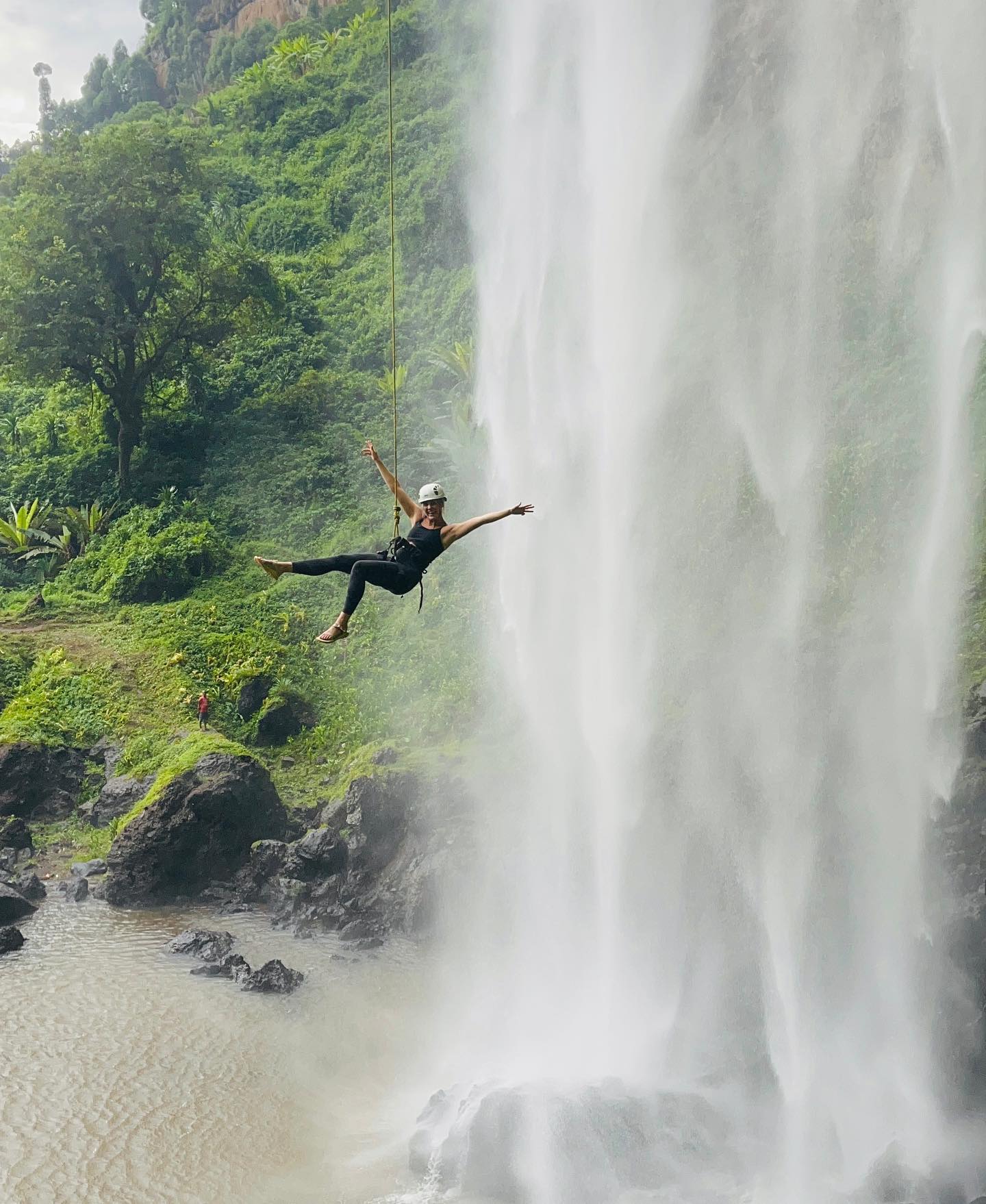 Tourist descending a cliff during Sipi Falls abseiling adventure